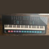 Černý elektronický klavír s bílými a černými klávesami. Na horním panelu je nápis MUSIC STATION, seznamy Voice List a Style List a digitální displej.…
