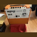 Zadní strana oranžového kytarového komba s bílým zadním panelem. Na panelu je nápis ORANGE CRUSH 35RT a logo značky Orange. Jsou zde vidět ovládací p…