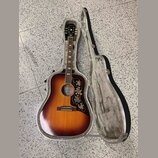 Akustická kytara s tělem typu dreadnought v barevné variantě sunburst, umístěná v otevřeném tvrdém kufru. Na hlavě je viditelné logo „Kepma“. Kytara…