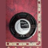Kruhový reproduktor s černým rámem a bílým štítkem v centru. Na štítku je uveden nápis Bugera™, VINTAGE GUITAR SERIES, POWER HANDLING 100 Watt, IMPED…