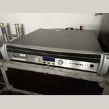 Stříbrný rackový zesilovač s černým horním krytem a mřížkou na přední straně. Na panelu jsou viditelné nápisy CROWN, SUB : IP-192.168.1.108 : ID-7 a…