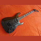 Černá elektrická kytara s tmavým hnedým hmatníkem a špičatou hlavou. Na hlavě je žlutý nápis KRAGLER. Nástroj má dva humbuckery, jeden jednosmykový s…