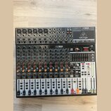 Černý mixovací pult značky behringer, model XENYX X1832USB. Zařízení obsahuje více vstupních kanálů s potenciometry, posuvníky a digitální displej v…