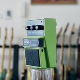 Zelený efekt pedál s nápisy Nobels, ODR-1 a Natural OVERDRIVE. Na horním ovládacím panelu jsou tři černé otočné knoflíky s popisky DRIVE, SPECTRUM a…
