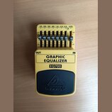 Žlutý kytarový pedál s černým horním panelem. Na černém panelu je logo a nápis behringer, níže je uveden model EQ700 a text GRAPHIC EQUALIZER. Zaříze…