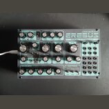 Analogový syntetizátor značky dre:adbox s modelem EREBUS. Zařízení má tyrkysový přední panel s mnoha ovládacími knoflíky a patch bayem s otvory pro k…