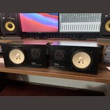 Dva studiové monitory v černých hranatých bednách. Na přední straně každého reproduktoru je bílý nápis YAMAHA a pod ním NS-10M STUDIO. Oba mají jeden…