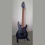 Elektrická kytara s modrým průsvitným povrchem a viditnou strukturou dřeva. Na hlavě hmatníku je bílý nápis Ibanez. Nástroj má dva humbuckery, jeden…