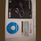 Fotografie zobrazuje krabici s USB MIDI rozhraním Roland UM-ONE a otevřený plastový obal s CD diskem a příručkou. Na krabici je nápis UM-ONE USB MIDI…