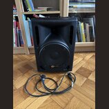 Černý kompaktní reproduktor s mřížkou a dvěma bočními rukojeťmi. Na spodní části mřížky je oranžové logo s nápisem soundnation. Před přístrojem leží…