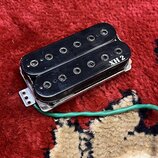 Černý humbucker s dvěma řadami magnetů a viditelnými póly. Na pravém okraji je bílý nápis XH 2. Snímač má kovové rámečky a z něj vede zelený kabel. P…