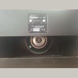 Černá reproduktorová bedna s texturovaným povrchem. Na zadní straně je kovový štítek s nápisy „Palmer“, „ENGINEERED BY Eminence“, „POWER HANDLING: WA…