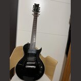 Černá elektrická kytara s dvojstupňovými humbuckery a bílým lemováním těla. Na hlavě je nápis "banez" a logo "Banez". Nástroj vykazuje mírné opotřebe…