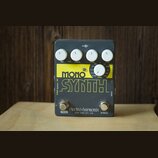 Šedý efekt pedál s žlutým nápisem MONO SYNTH. Na horní části jsou čtyři bílé oválné knoflíky s popisky DRY VOL, SYNTH, SENS a CTRL. Uprostřed je jede…
