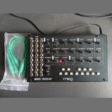 Černý analogový syntetizátor s bílými nápisy a ovládacími prvky. Na spodní liště je uveden název MAVIS MONOPHONIC ANALOG SYNTHESIZER VOICE a logo moo…