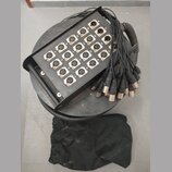 Černý kulatý rozvodový box s madlem, který obsahuje 16 ženských XLR konektorů. Konektory jsou očíslovány od 1 do 16 a vedle některých jsou vidět písm…