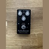 Černý kytarový efekt s nápisem KokoBoost RELOADED a logem Suhr. Na horní straně jsou tři ovládací knoflíky s popisky Boost, Freq a MidBoost (u prostř…