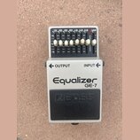 Kytarový pedál Equalizer GE-7 značky BOSS v šedé barvě. Horní ovládací panel je černý s bílými nápisy 100, 200, 400, 800, 1.6k, 3.2k, 6.4k a Level, s…