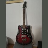 Elektrická kytara s polodupatým korpusem v červeně-černém sunburst provedení. Na hlavě hmatníku je viditelné logo Samick. Nástroj má dva snímače, čty…
