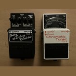 Dvě efektové pedály značky BOSS umístěné vedle sebe. Levý pedál je černý s nápisy COSM, Fender '65 Deluxe Reverb-Amp a FDR-1. Pravý pedál je bílý s n…
