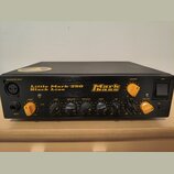 Černý basový zesilovač s nápisy Little Mark 250 Black Line a logem Markbass. Přední panel obsahuje žluté a černé ovládací knoflíky s popisky GAIN, LO…