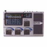 Šedý kytarový procesor s nápisem GNX1 GuitarFx GUITAR PROCESSOR. Displej zobrazuje text HYBRID 10 a vedle jsou umístěny ovládací tlačítka a potenciom…
