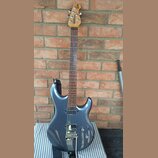 Modře metallic elektrická kytara s hnědým hmatníkem a dřevěnou hlavou. Na hlavě je svisle napsaný nápis Ibanez. Kytara má jeden humbucker u kobylky,…