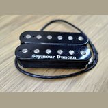Černý humbucker s dvěma řadami magnetických pólů. Na spodním snímači je bílý nápis Seymour Duncan. Povrch plastového krytu vykazuje drobné škrábance…