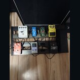 Kytarový efektový pedalboard s dvěma řadami pedálů. V horní řadě jsou od levy pedály s nápisy JOYO Classic Flanger, Boss BF-2 Flanger, nečitelný zele…