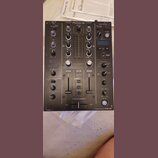Černý dvoukanálový DJ mixér s nápisem Pioneer DJ v horní části. Na spodním pravém rohu je uveden model 2 CHANNEL DJ MIXER DJM-450. Přístroj obsahuje…