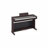 Digitální piano v tmavě hnědém dřevěném provedení s klasickým tvarem. Nástroj má bílé a černé klávesy a nad nimi je umístěn jednoduchý notový pult. N…