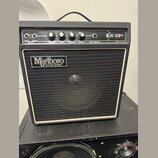 Černý kytarový kombozesilovač s bílým lemováním kolem mřížky. Na přední mřížce je nápis „Marlboro SOUND WORKS“ a na ovládacím panelu označení „G-10R“…