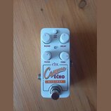 Bílý efektový pedál s nápisy ehx, Canyon ECHO a NYC DSP. Na horní straně jsou čtyři bílé otočné knoflíky s červenými značkami a popisky BLEND, DELAY,…