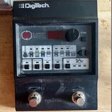 Černý efektový procesor s nápisem Digitech na horní hraně. Na předním panelu je uveden název ELEMENT GUITAR EFFECTS PROCESSOR a jsou umístěny ovládac…