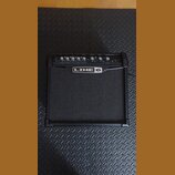 Černý kytarový kombo zesilovač s látkovou mřížkou. Na horním ovládacím panelu jsou knofíky s popisky DRIVE, BASS, MID, TREBLE, CHAN VOL a MASTER. Upr…