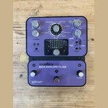 Fialový efekt pedál s nápisem soundblox® PRO BASS ENVELOPE FILTER a logem SOURCE AUDIO. Zařízení má několik ovládacích knoflíků, přepínačů a v horní…