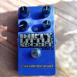 Modrý efekt pedál s čtyřmi černými otočnými ovladači. Na povrchu je velký nápis DIRTY LITTLE SECRET MKII a v dolní části logo catalinbread. Pedál vyk…