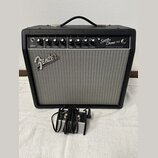 Černý kytarový kombozesilovač s šedou textilní maskou reproduktoru. Na horním ovládacím panelu je nápis Super Champ x2 a VINTAGE MODIFIED TUBE AMPLIF…