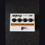 Bílý kytarový zesilovač s nápisy ORANGE TERROR STAMP. Na horní části jsou čtyři černé ovratové ovládací knoflíky s popisy VOLUME 1, VOLUME 2, SHAPE a…