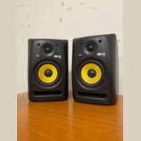 Dva černé studiové monitory s žlutými membránami basových reproduktorů. Na obou je vidět logo KRK a nápis ROKIT 5. Povrch krytů je matný, v dolní čás…