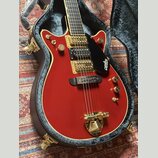 Červená elektrická kytara s gold hardwarem v černém tvrdém kufru. Na černé plechovce je bílý nápis GRETSCH. Nástroj má dva snímače, zlaté knoflíky a…