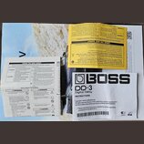 Fotografie zobrazuje papírový návod k obsluze efekt pedálu. Na bílém podkladu je výrazné černé logo BOSS a název modelu DD-3 Digital Delay. Text obsa…