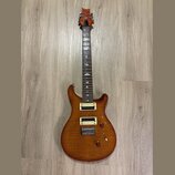 Elektrická kytara s tělem z plaménkového dřeva v hnědém odstínu a dvěma humbuckery s krémovými rámečky. Na hmatníku jsou vložky ve tvaru ptáků a na h…