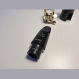 Černý munzpun na saxofon s zlatými nápisy. Na povrchu je uveden model Rc, značka MEYER a text MADE IN U.S.A. V horní části je vidět zlatý ligaturek a…