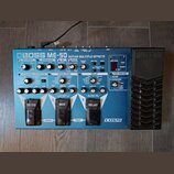 Modrý efektový pedál Boss ME-50 Guitar Multiple Effects. Na horní straně jsou různé ovládací knofíky, přepínače a červené digitální displeje. V dolní…