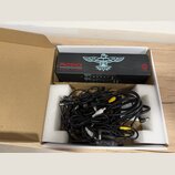 Černý napájecí adaptér s nápisy PHOENIX CLEAN POWER a HANDMADE IN THE USA, doplněný bílým logem ptáka. V krabici s polystyrenovými vložkami se nacház…