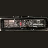 Zadní strana černého zesilovače značky PHONIC, model MAX 2500. Jsou zde vidět vstupy INPUT (XLR a jack), výstupy OUTPUT (SpeakON) a ventilátor. Na št…