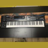 Černý syntetizátor s bílými a černými klávesami. Na pravé straně je bílý nápis Roland a pod ním model JUNO-60. Horní panel obsahuje různé ovládací pr…