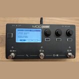 Černý kompaktní efektový procesor s nápisem MOD DWARF. Displej zobrazuje text DEVICE INFO, CURRENT RELEASE: v1.13.5.3315 a DEVICE SERIAL: MDWD02M02-0…
