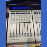 Šedý kontrolní panel NCU Extender PRO by LOUD Technologies, Inc. s modrým displejem, na kterém je stejný nápis a verze 04.0.3. Zařízení obsahuje osm…